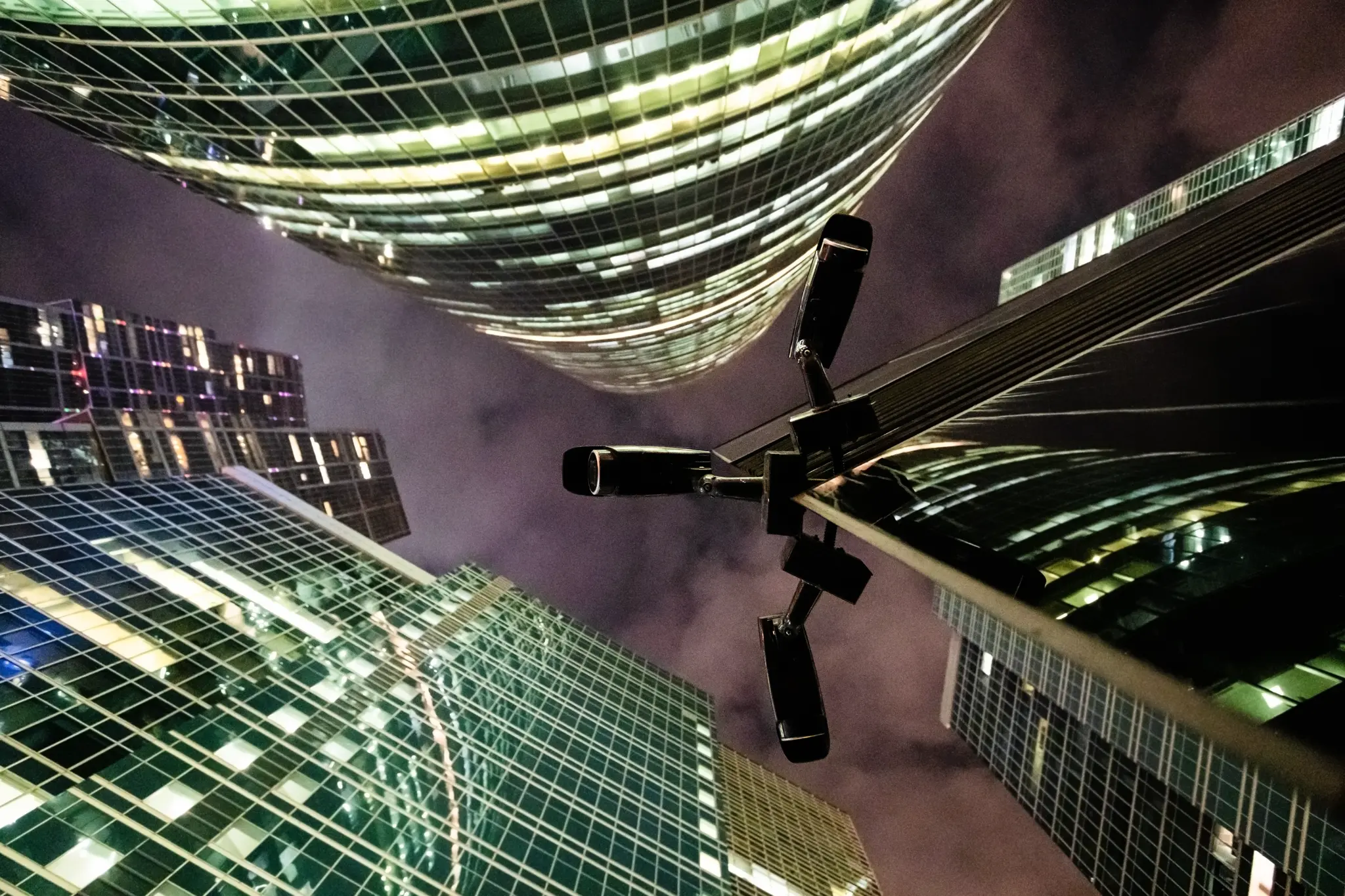 CCTV surveillance cameras overlooking cityscape at night from high-rise buildings